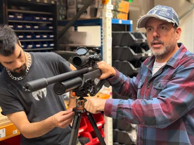 Danny Lenihan, founder of 3 Legged Thing, examines a rifle mounted on one of the company’s tripods during product testing for the shooting sector.